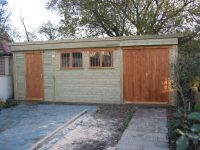 This building is a pent roof workroom and features 2 x garage windows with grilles, framed ledged & braced double and single doors. 